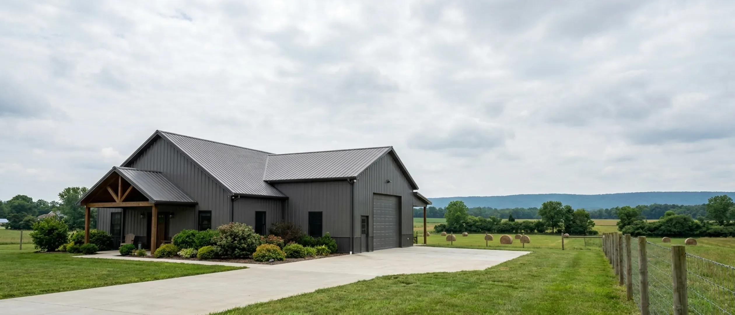 A completed barndominium with a covered entry porch and an attached shop bay, photographed in flat overcast daylight.